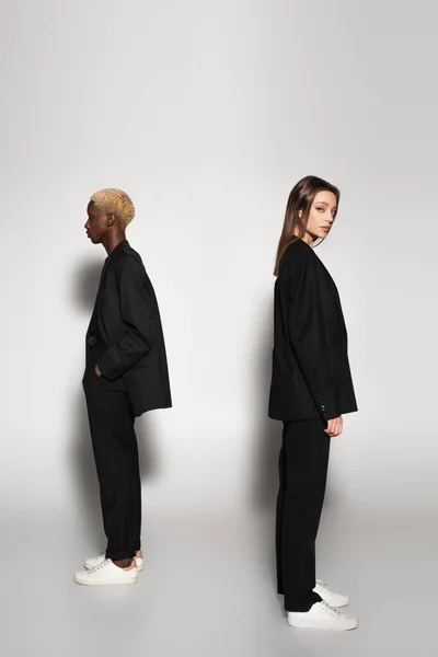 Stylish Interracial Couple Black Suits White Sneakers Standing Back Back — Stock Photo, Image