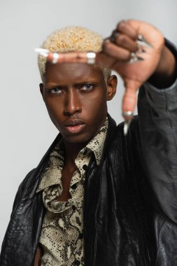 Gri ellerde metal tırnaklarıyla poz veren çekici Afrikalı Amerikalı bir adam.