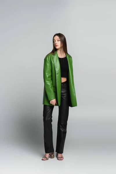 ブルーネット女性で緑の革のジャケット 黒のズボンとサンダル離れてグレー — ストック写真