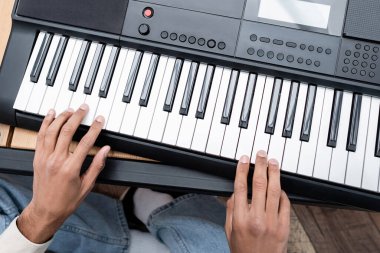 Cropped view of african american man playing synthesizer at home  clipart