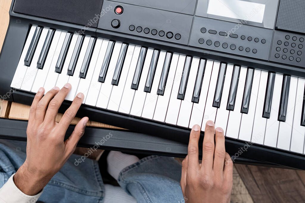 Cropped view of african american man playing synthesizer at home 