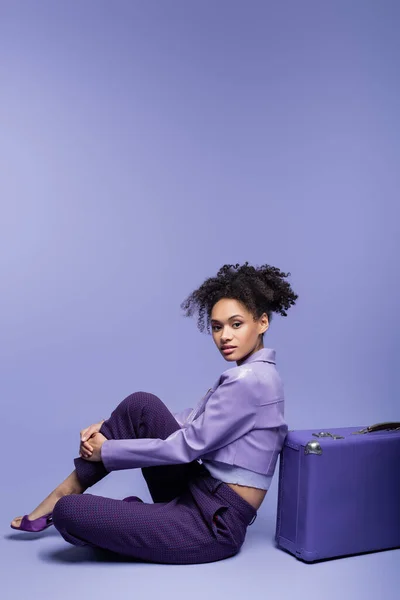 Longitud Completa Joven Rizada Mujer Afroamericana Sentada Cerca Maleta Púrpura — Foto de Stock