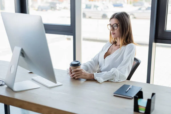 Empresária Óculos Segurando Copo Papel Olhando Para Monitor Computador Escritório — Fotografia de Stock