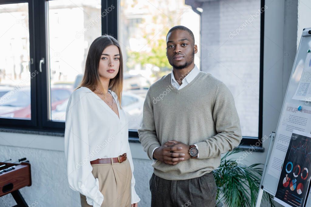interracial businessman and businesswoman posing in office 