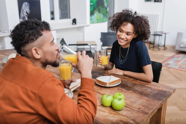 幸せなアフリカ系アメリカ人女性持っています昼食とともにぼやけたボーイフレンド飲みオレンジジュース — ストック写真