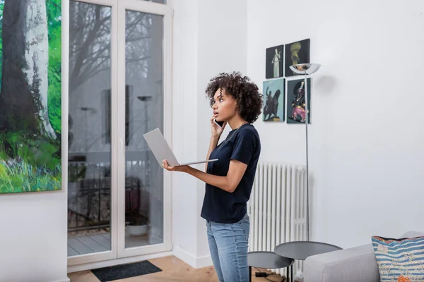 Young African American Woman Talking Smartphone Holding Laptop Living Room — Stock Photo, Image