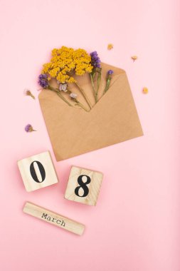 Ağaç küplerin yanında kuru çiçeklerle kaplı el sanatları zarfındaki kuru çiçeklerin üst görüntüsü. 