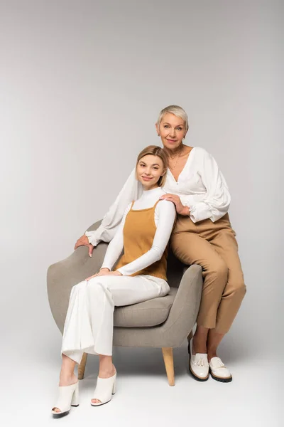 Full Length Positive Young Daughter Sitting Armchair Smiling Mother Grey — Stock Photo, Image