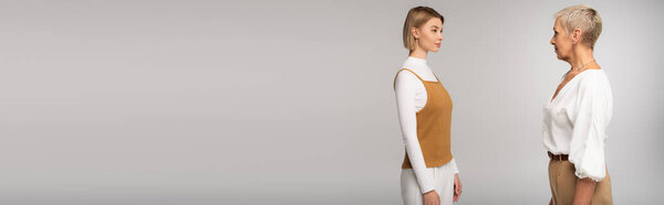 young daughter and mother looking at each other isolated on grey, banner