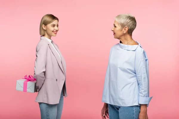 Cheerful Young Woman Holding Present Back Mature Mother Isolated Pink — Stock Photo, Image