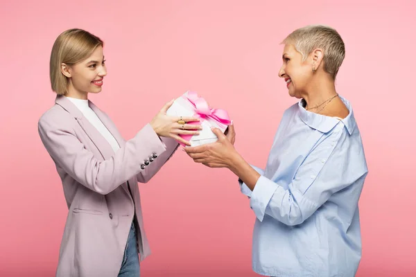 Mutlu kadın, neşeli olgun anneye pembe bir hediye veriyor.