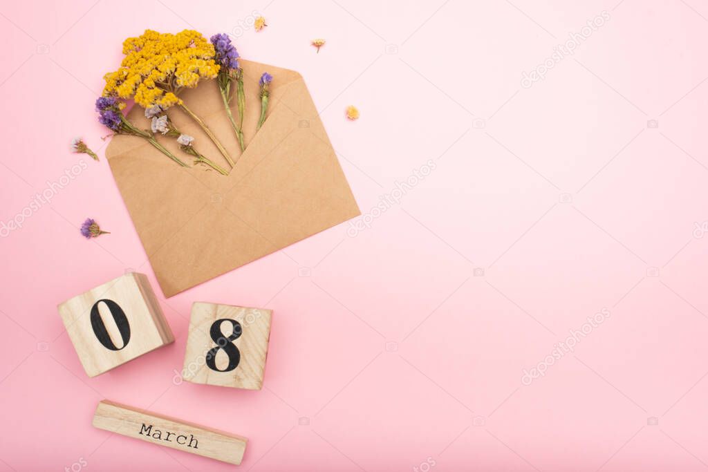 top view of dry flowers in craft envelope with dried flowers near wooden calendar cubes with 8 march on pink 