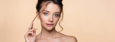 Dudak ısıran ve kameraya bakan genç bir kadın bej rengi, pankartta izole edilmiş. 