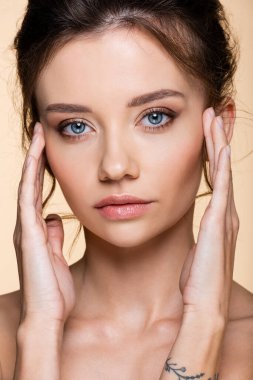 Dövmeli model bej üzerinde izole edilmiş yüzlere dokunuyor. 