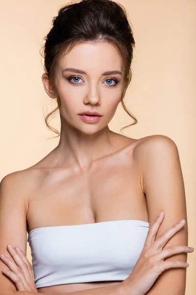 Pretty model in white top crossing arms isolated on beige