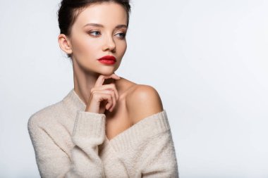 Çıplak omuzlu, gözlerden uzak, beyaz süveter giyen moda bir model.