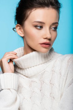 Mavi üzerine izole edilmiş beyaz süveterin esmer model dokunmatik yakası.