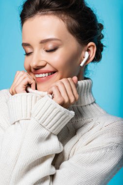 Mavi üzerine izole edilmiş süveterin kulaklık tasmasında pozitif model.