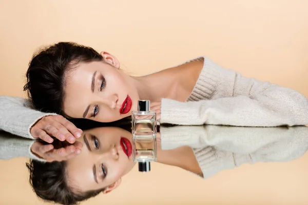 Vacker Modell Med Röda Läppar Tittar Parfymflaska Spegeln Isolerad Beige — Stockfoto