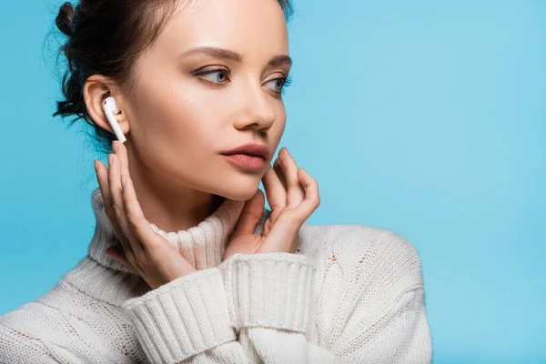 Jonge Vrouw Gebreide Trui Oortelefoon Kijken Weg Geïsoleerd Blauw — Stockfoto