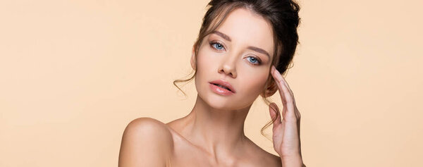 Красивая модель с обнаженными плечами, смотрящая на камеру, изолированную на бежевом, баннере 