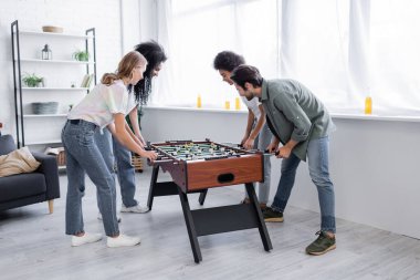 Mutlu ırklar arası kadınlar ve masa futbolu oynayan erkek 