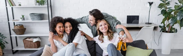 Happy Man Holding Bottles Beer Hugging Interracial Women Sofa Banner — Stock Photo, Image