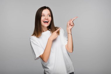 Heyecanlı kadın parmaklarıyla işaret ederken, izole bir şekilde griye bakıyor.