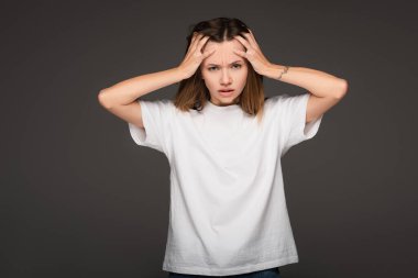 Koyu gri renkte izole edilmiş migrenden muzdarip bir kadın kafasına dokunuyor.