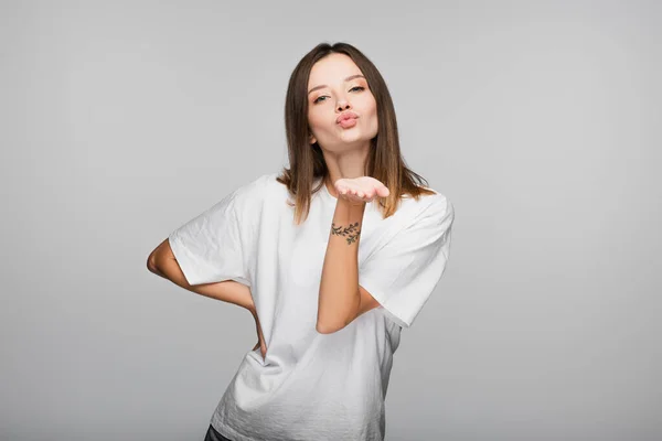 Jonge Vrouw Met Hand Middel Blazen Kus Geïsoleerd Grijs — Stockfoto