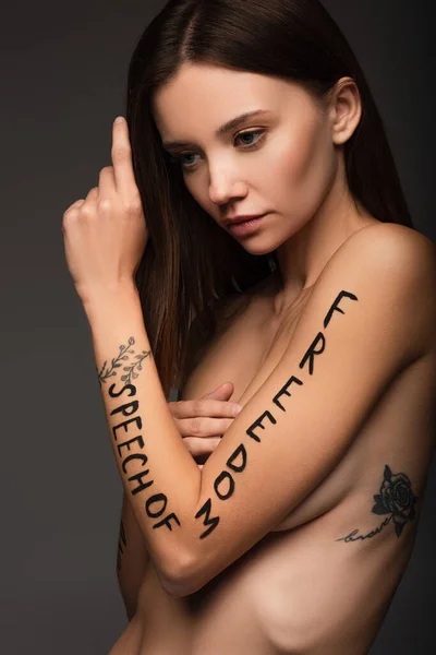 young brunette woman with freedom of speech lettering on arm isolated on dark grey