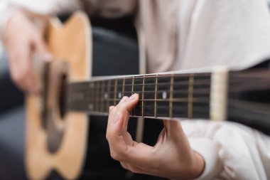Akustik gitar çalan genç bir kadının kısmi görüntüsü