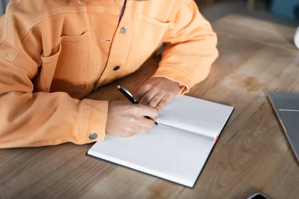 Vista Recortada Estudiante Chaqueta Naranja Escribiendo Cuaderno Mientras Aprende Casa — Foto de Stock