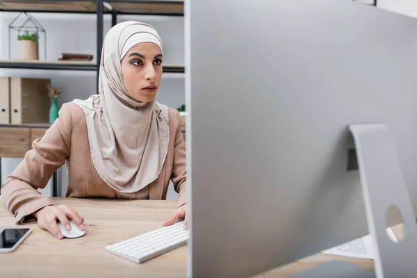 Muslimská Žena Pracující Blízkosti Rozmazané Monitoru Počítače Smartphone Prázdnou Obrazovkou — Stock fotografie