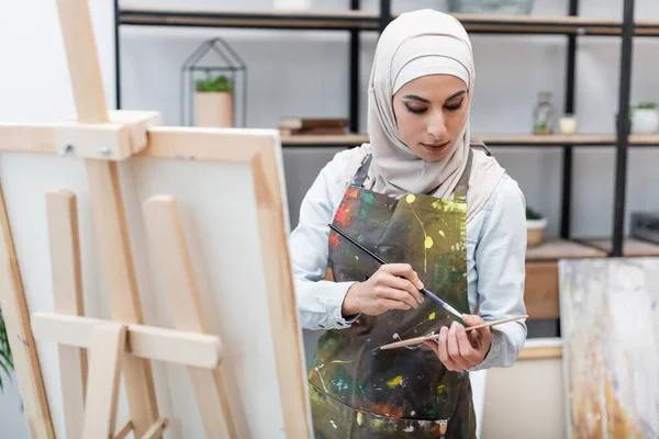 Ung Arabiskt Kvinna Med Palett Och Pensel Nära Staffli Hemstudio — Stockfoto
