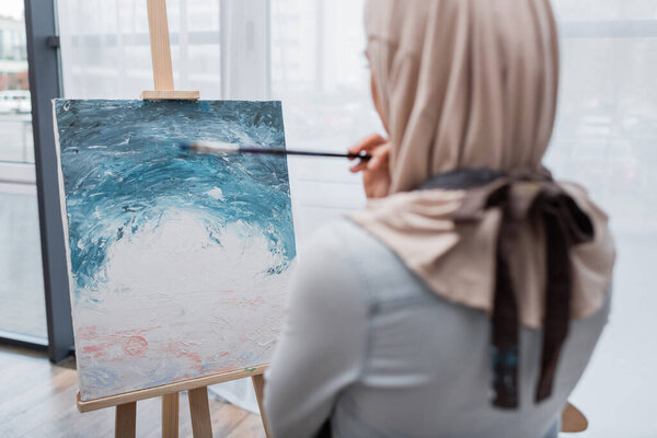 back view of blurred muslim woman drawing picture at home