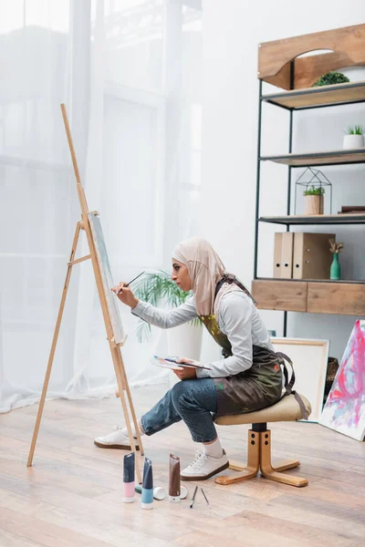 Vista Lateral Mujer Musulmana Dibujo Caballete Cerca Tubos Pintura Suelo — Foto de Stock