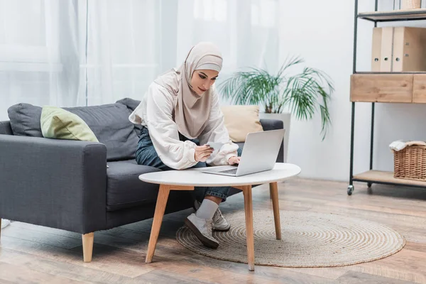 Мусульманська Жінка Хіджабі Тримає Кредитну Картку Використовує Ноутбук Дивані Вдома — стокове фото