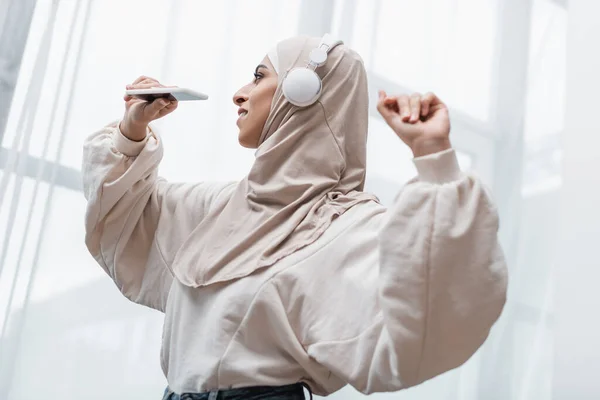 Happy Arabian Woman Hijab Headphones Holding Smartphone While Dancing Home — Stock Photo, Image