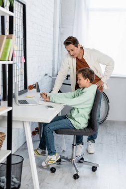 Gülümseyen çocuk defterin yanına yazı yazıyor ve babam evde. 