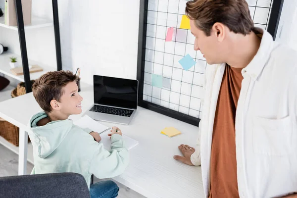 Side View Smiling Boy Writing Notebook Looking Dad Home — Stock Photo, Image