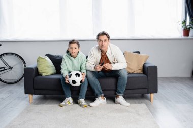 Evde futbol seyreden baba ve çocuk. 