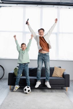 Evde futbol topunun yanında zıplayan uzaktan kumandalı heyecanlı bir aile. 