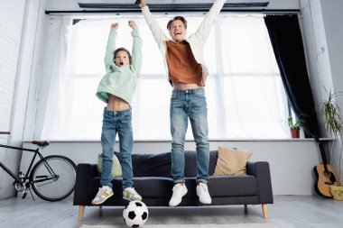 Neşeli baba oğul futbol maçı izleyip evde zıplıyorlar. 