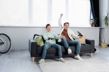 KYIV, UKRAINE - 11 Ekim 2021: joystickli adam evdeki çocuğun yanında evet işareti gösteriyor 