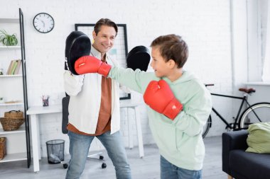 Gülümseyen çocuk evde babasıyla boks yapıyor. 
