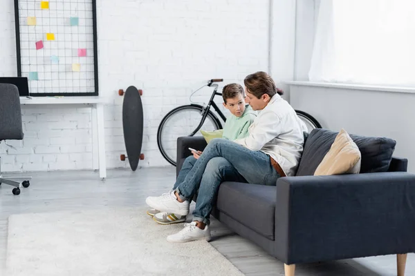 Jongen Met Smartphone Praten Met Papa Bank Woonkamer — Stockfoto