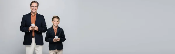Позитивные Мальчик Папа Куртках Держащих Смартфоны Изолированы Сером Баннер — стоковое фото