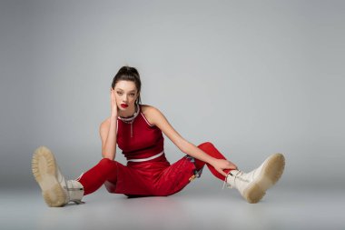 Kırmızı spor elbiseli ve gri çizmeli modaya uygun genç bir model.
