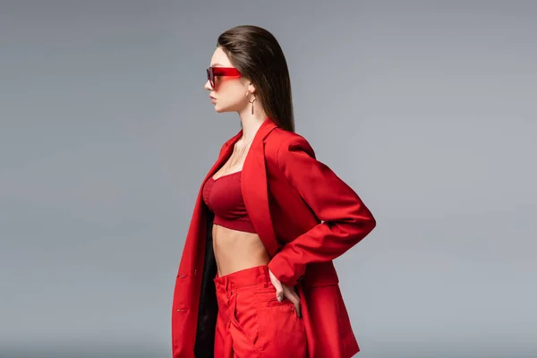 Widok Boku Młodej Kobiety Modnym Czerwonym Garniturze Okularach Przeciwsłonecznych Pozowanie — Zdjęcie stockowe